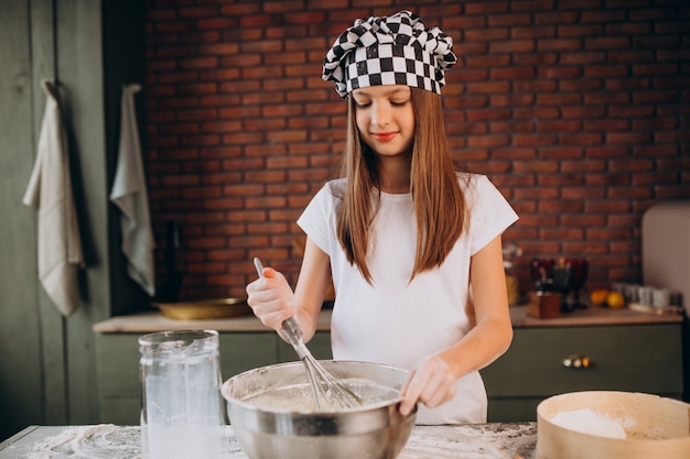 Young little girl baking pastry at the kitchen for breakfast