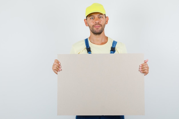 Young loader holding blank canvas and smiling in uniform front view.