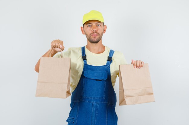 Young loader holding brown paper bags in uniform front view.