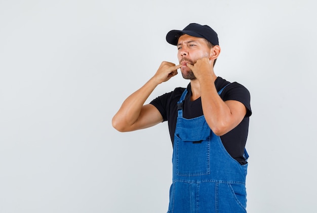 Young loader whistling in uniform and looking pensive , front view.