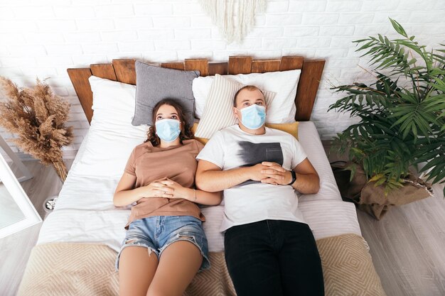 Young lovely couple lying on bed with face blue mask