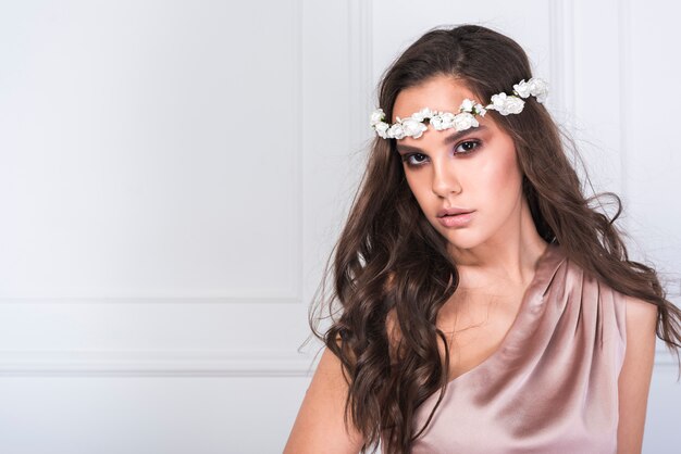 Young lovely lady in dress with flowers wreath on head