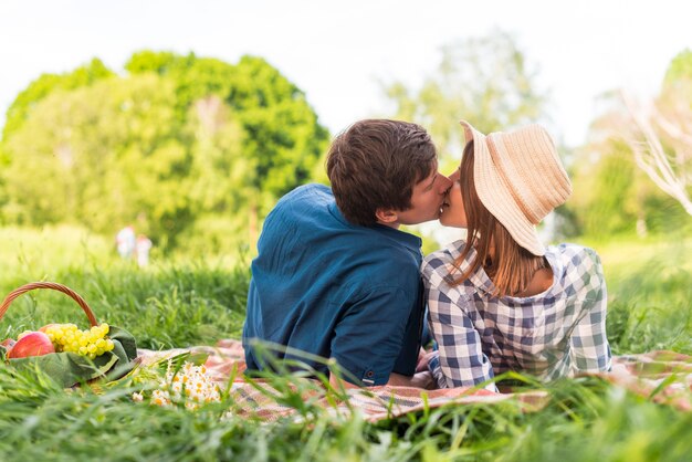 若い恋人たちが芝生の上の外の毛布にキス