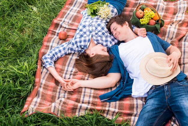 Young lovers lying on plaid in forest