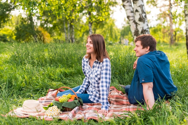 Young lovers sitting on blanket in birch forest