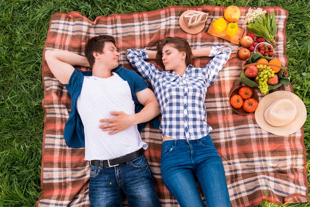 Young lovers taking nap on blanket outside