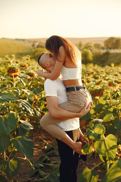 Young loving couple is kissing in a sunflower field. Portrait of couple posing in summer in field.