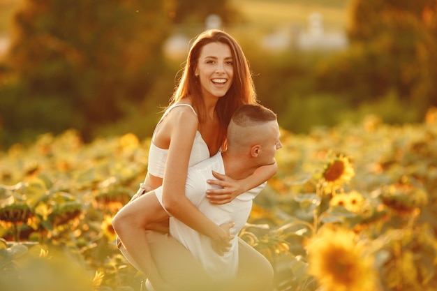 Young loving couple is kissing in a sunflower field. Portrait of couple posing in summer in field.