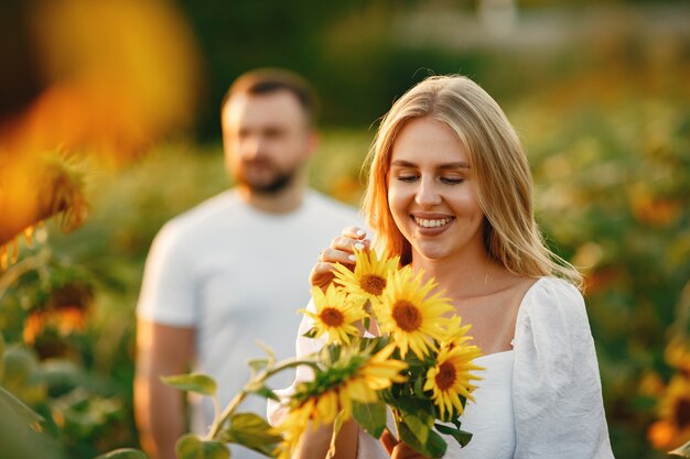 ひまわり畑で若い夫婦がキスします。フィールドで夏にポーズのカップルの肖像画。