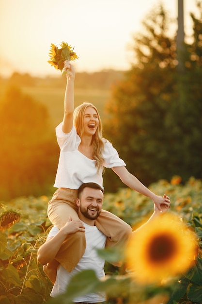 Young loving couple is kissing in a sunflower field. Portrait of couple posing in summer in field.