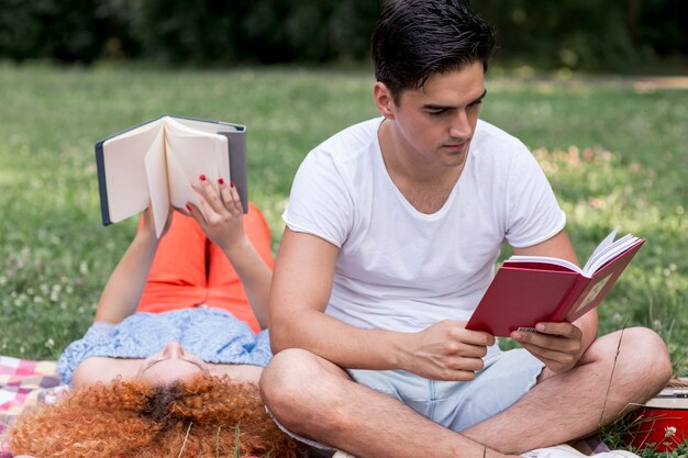 Молодые любящие пары, чтение книг на открытом воздухе