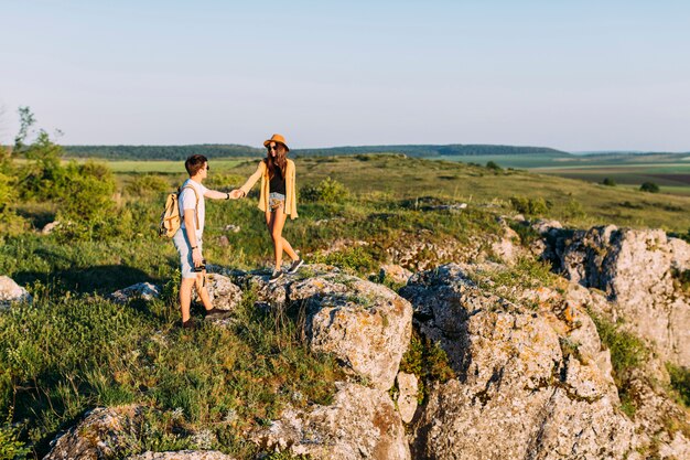 Young loving couple standing on rock holding hands