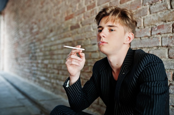 Free Photo young macho boy wear on blac stylish jacket smoking cigarette on streets