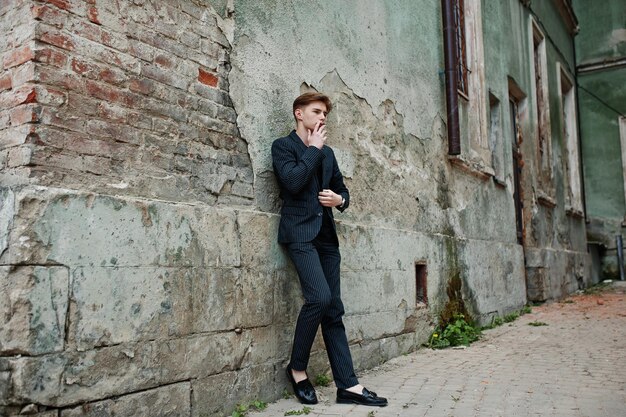 Young macho boy wear on blac stylish jacket smoking cigarette on streets