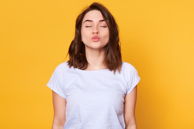 Young magnetic brunette lady standing with closed eyes