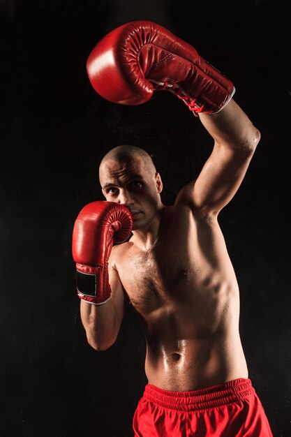 The young male athlete kickboxing on a black background