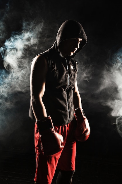 青い煙の背景に立っている若い男性アスリートキックボクシング