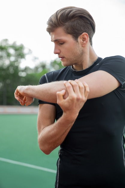 Молодой мужчина спортсмен делает упражнения на растяжку на открытом воздухе