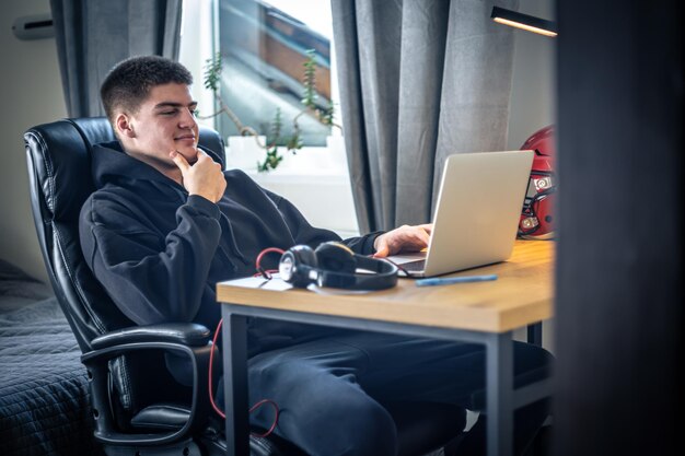 A young male athlete sits in front of a laptop in his room
