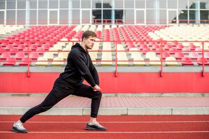 Young male athlete warming up in stadium