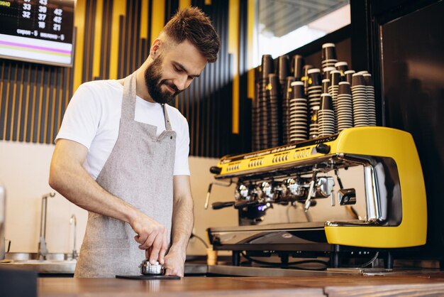 コーヒーショップでコーヒーを準備する若い男性のバリスタ