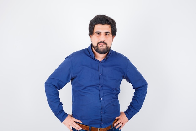 Young male biting his lip in royal blue shirt and looking greedy , front view.