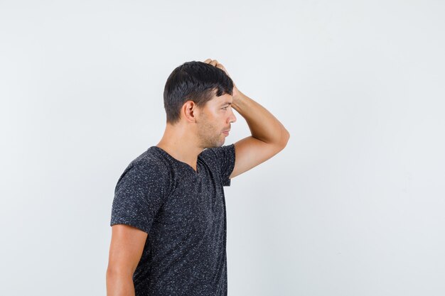 脇を見て困惑している黒いTシャツの若い男性。