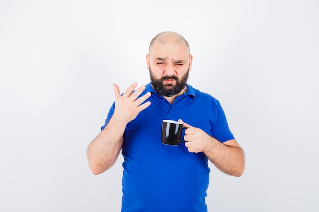 Young male in blue shirt feeling strange smell , front view.