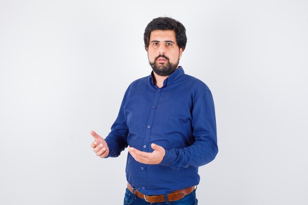 Young male in blue shirt looking confused , front view.