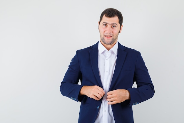 Young male buttoning his jacket while standing in shirt