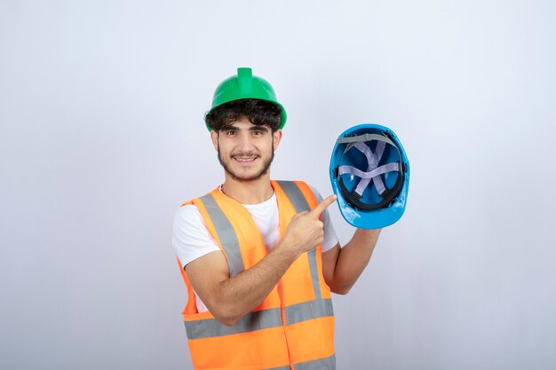 Young male construction worker holding hardhat on white background. High quality photo