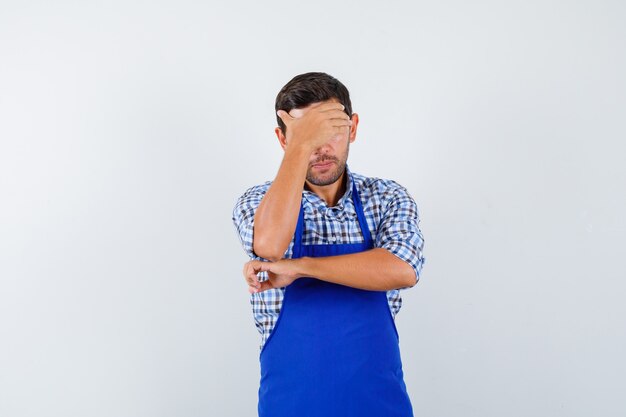 Young male cook in a blue apron and a shirt