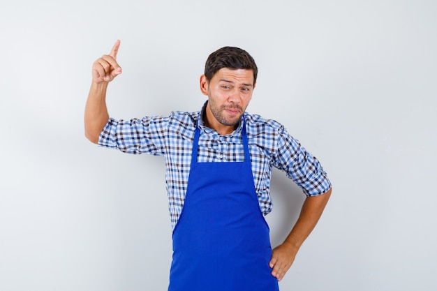 青いエプロンとシャツを着た若い男性料理人