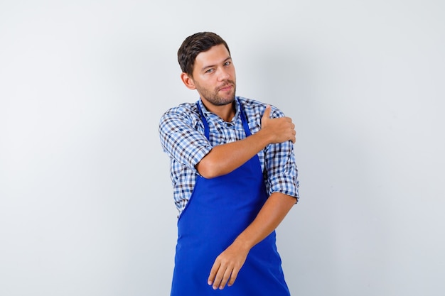 Young male cook in a blue apron and a shirt