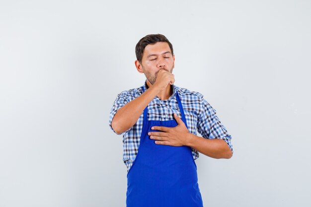 Young male cook in a blue apron and a shirt