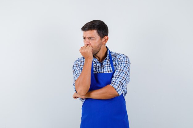 Молодой мужчина-повар в синем фартуке и рубашке