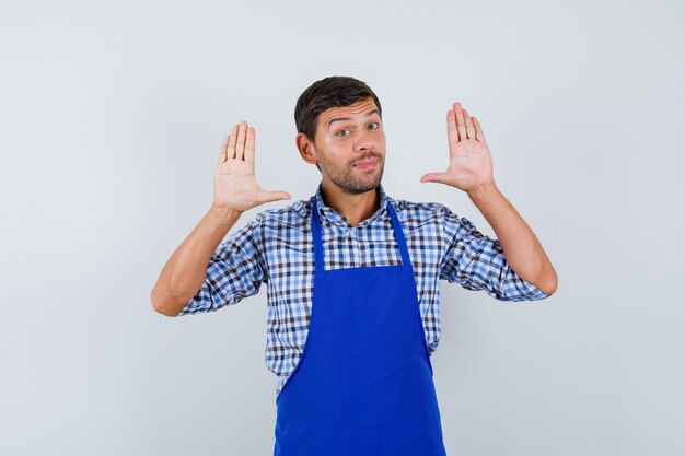 Young male cook in a blue apron and a shirt