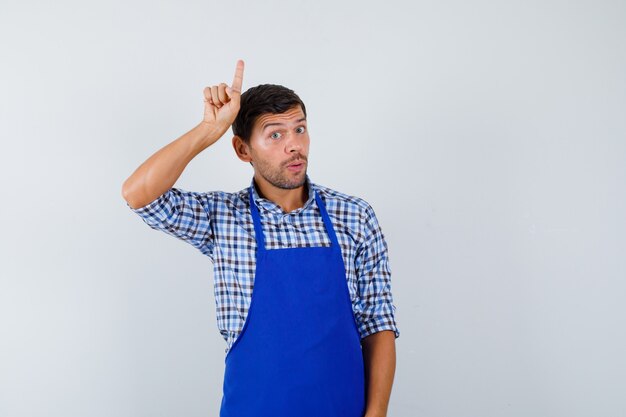 青いエプロンとシャツを着た若い男性料理人