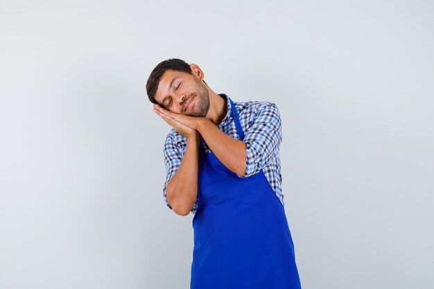 Young male cook in a blue apron and a shirt