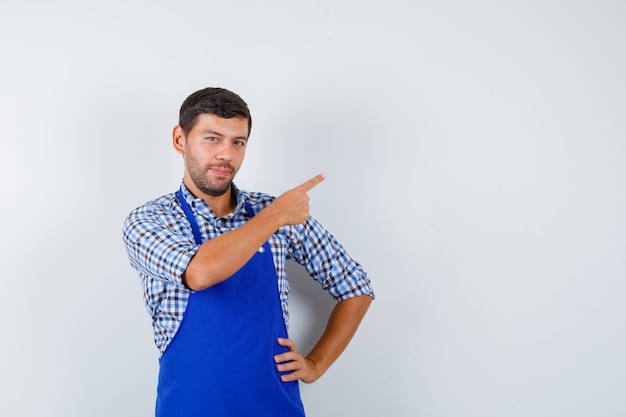 Giovane cuoco maschio in un grembiule blu e una camicia