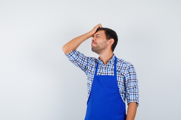 Foto gratuita giovane cuoco maschio in un grembiule blu e una camicia