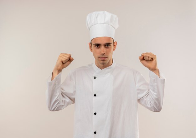  young male cook wearing chef uniform doing strong gesture on isolated white wall