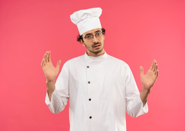 young male cook wearing chef uniform and glasses showing size 