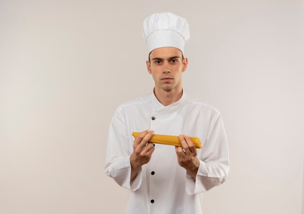 молодой мужчина-повар в униформе шеф-повара держит спагетти на изолированной белой стене с копией пространства