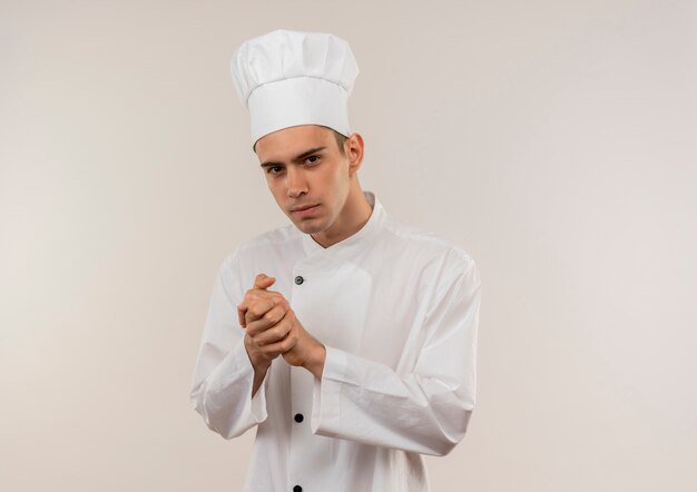  young male cook wearing chef uniform showing handshakes gesture on isolated white wall with copy space