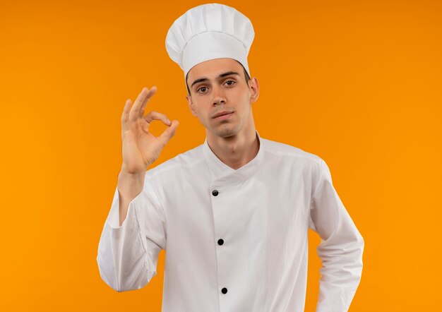  young male cool wearing chef uniform showing okey gesture on isolated yellow wall