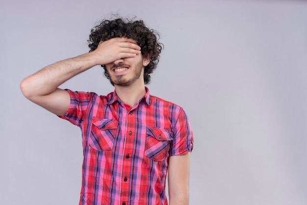 Young male curly hair isolated  colorful shirt hand over eyes