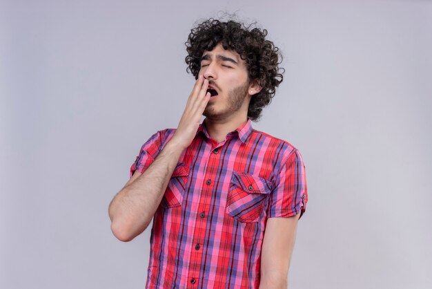 Young male curly hair isolated  colorful shirt yawning