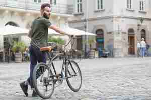 Foto gratuita giovane ciclista maschio con la sua bicicletta in strada