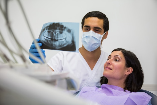 Young male dentist examining X-ray with the female patient